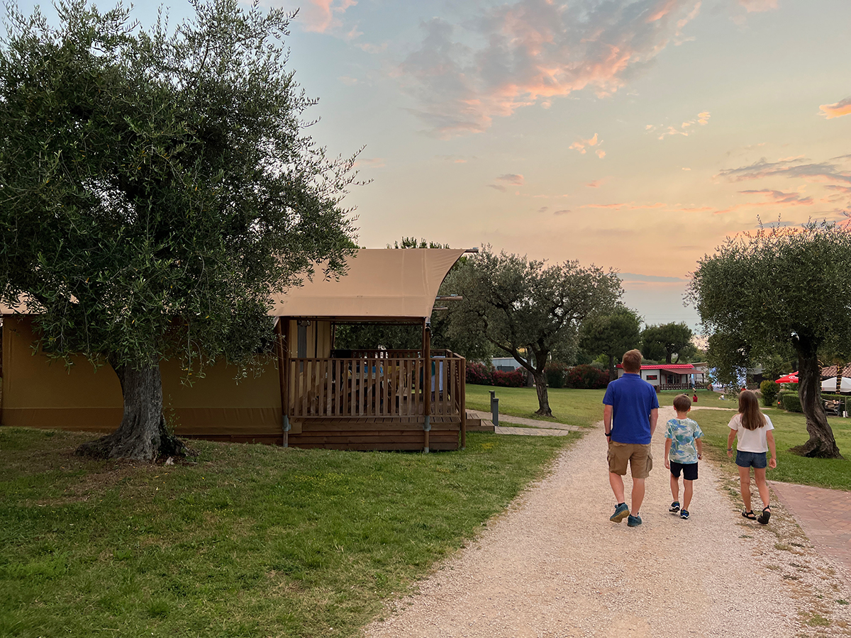 Papà e due bambini passeggiano nel campeggio al Camping Park delle Rose