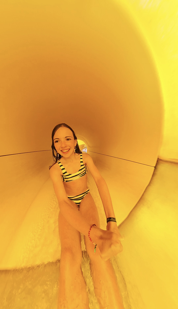 bambina dentro lo scivolo giallo del parco acquatico
